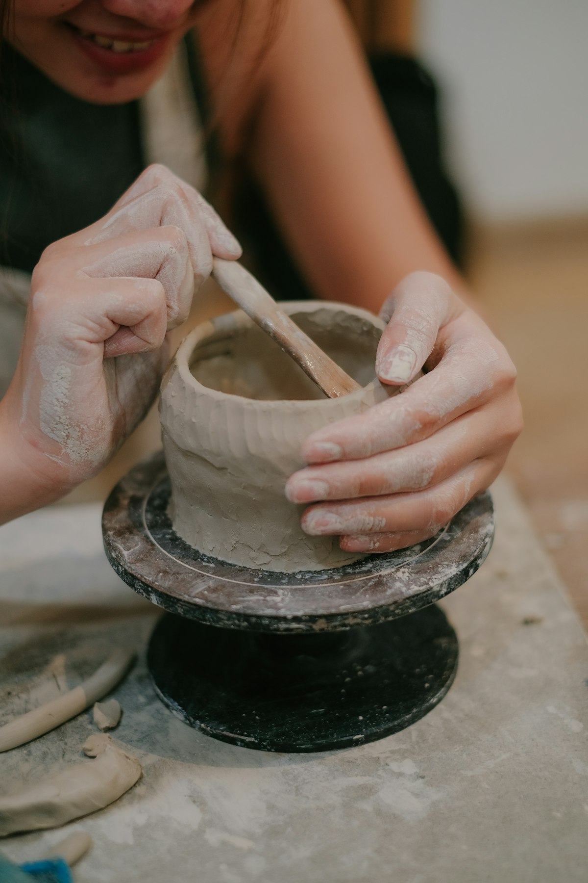 Hands shaping a vessel from clay