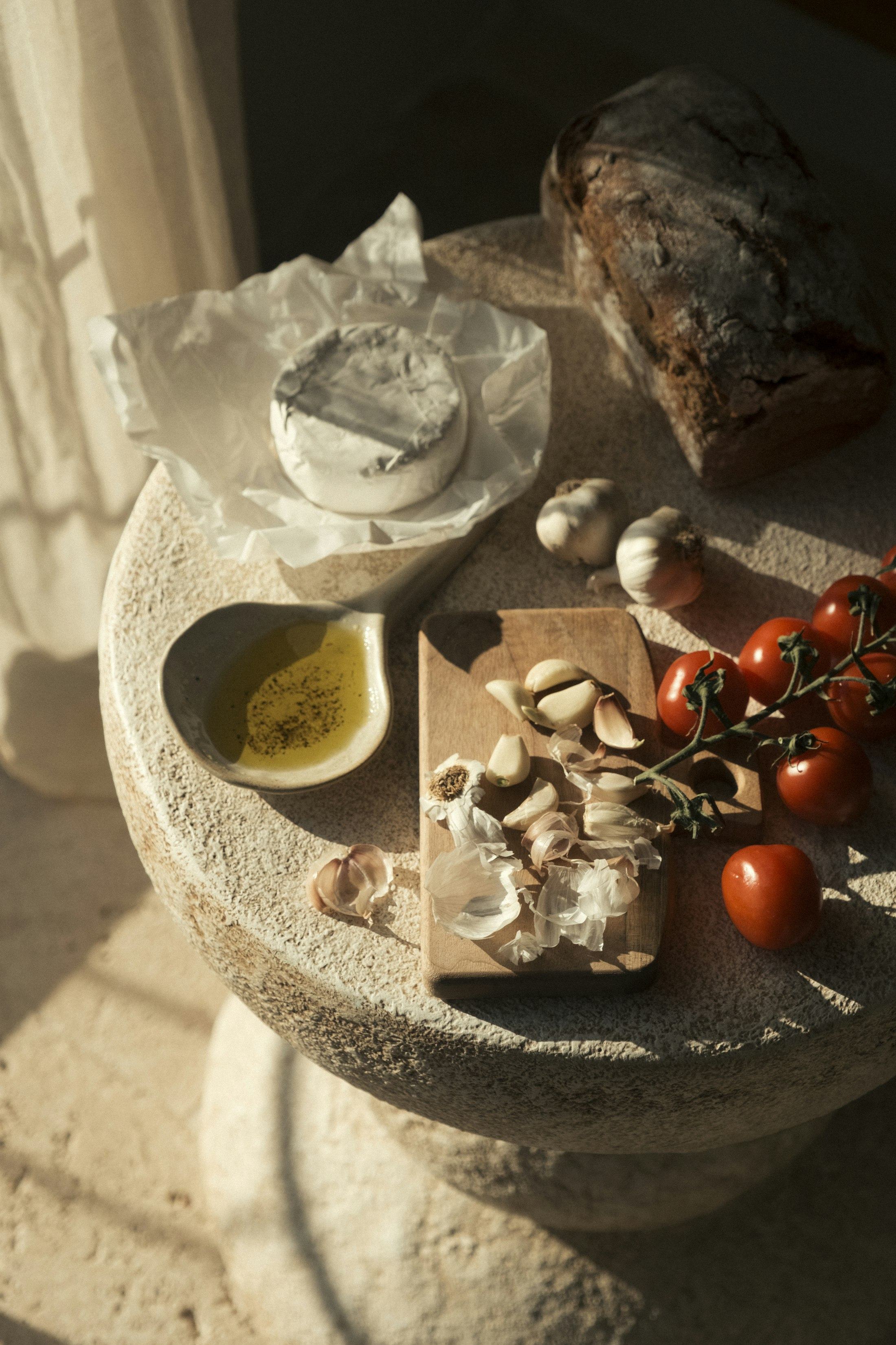 Bread, cheese, garlic and tomatoes on a stone table