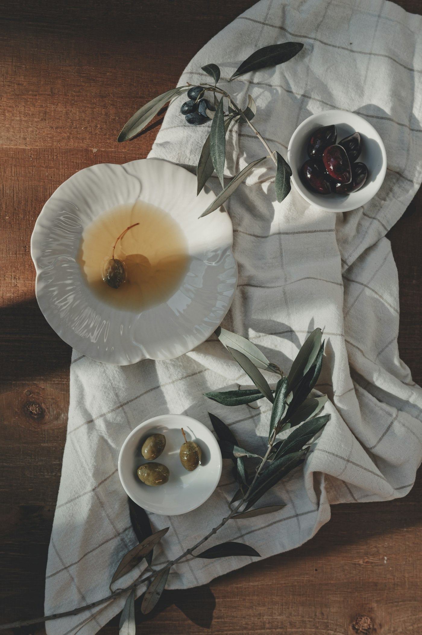Olives and bread on linen with an olive branch